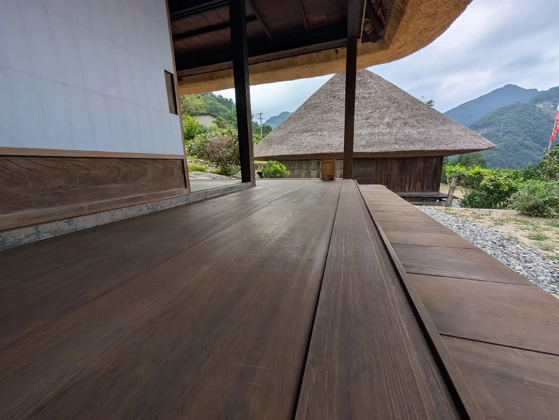 縁側の板の木目と、その先に広がる茅葺き屋根の景色